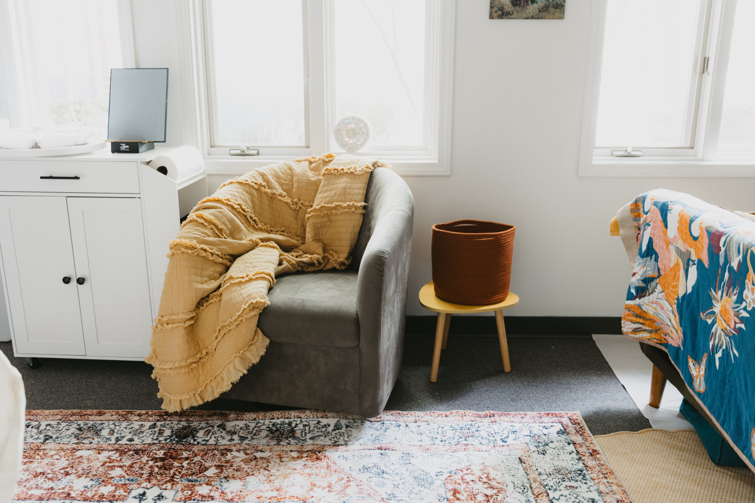 Sunlit corner of the Beyond the Sun office with an armchair and soft throw